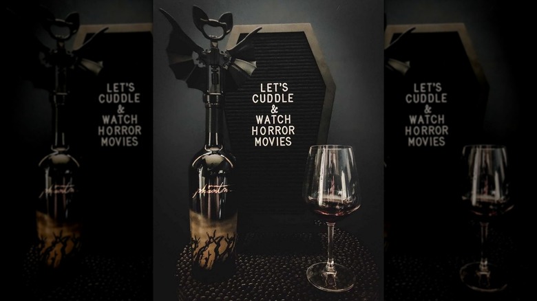Wine bottle and glass in front of coffin letter board