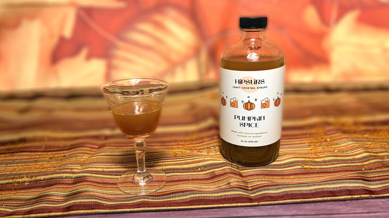 Glass and bottle of HipStirs pumpkin spice syrup