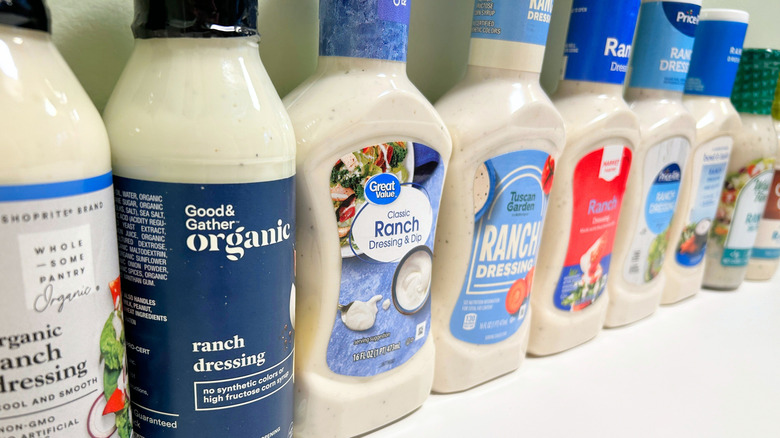 Close up of several bottles of ranch from different brands standing in a line