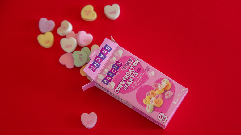 Box of Brach's candy hearts with hearts spilling out onto red background.