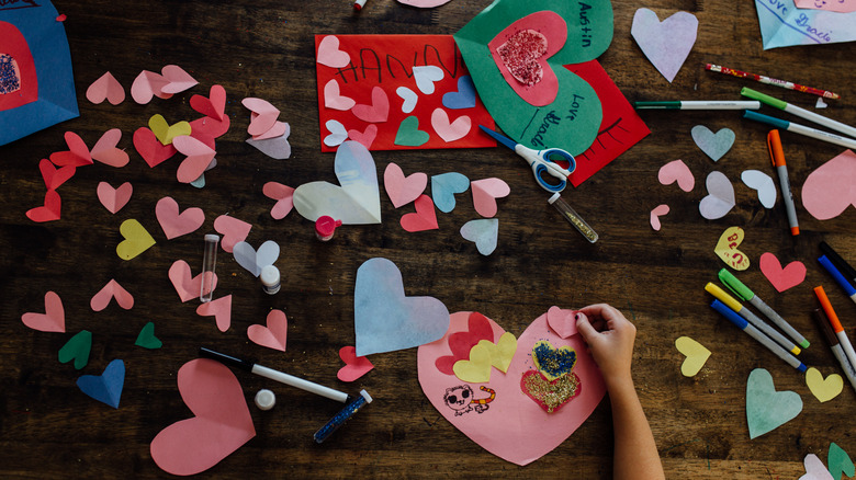 A child hand-making cards for a Valentine's Day party.