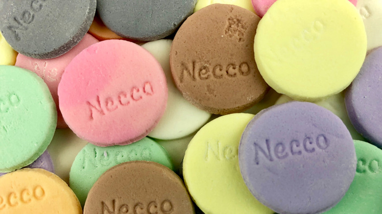 Round Necco candy wafers in various colors, stamped with the company name.