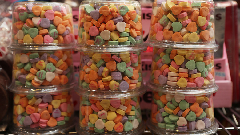 Stacked clear containers containing multi-colored candy hearts.