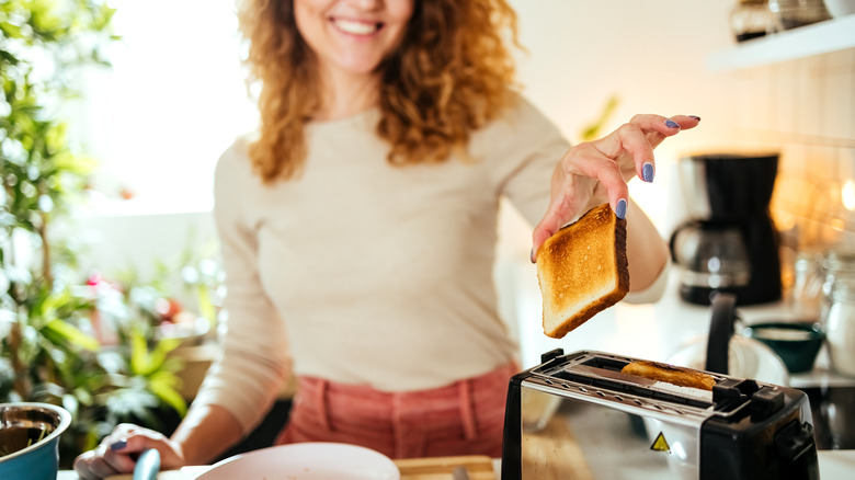 woman putting bread in toaster