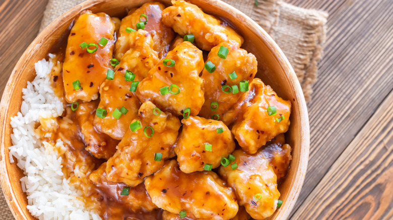 Bowl of orange chicken with rice and green onions