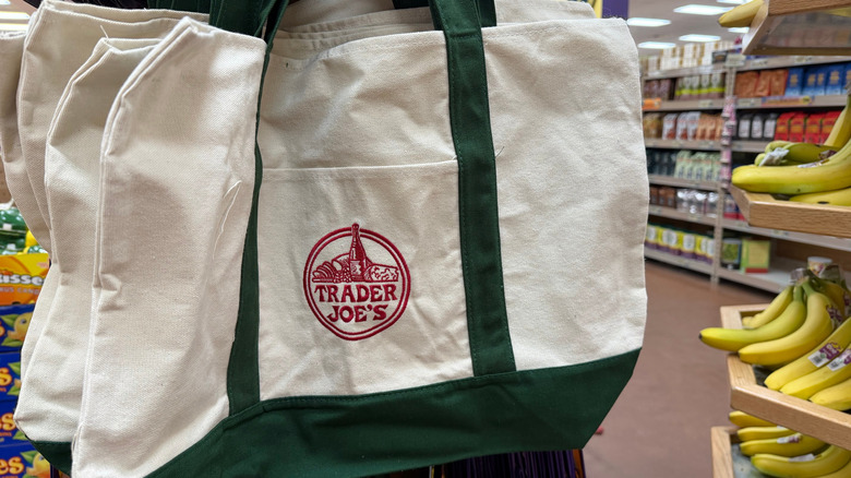 Trader Joe's canvas bags hanging in the store next to bananas