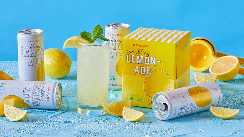 Sparkling lemonade in glass with box on blue surface