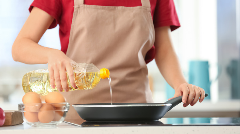 Person pouring oil into frying pan