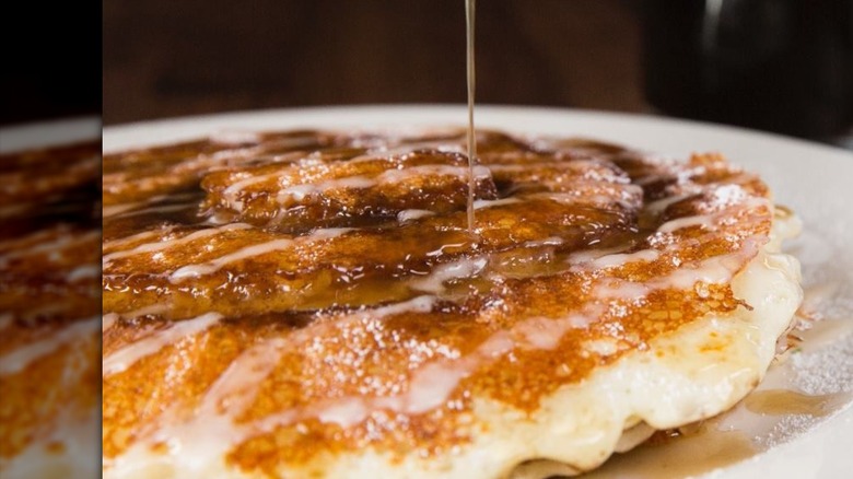 Close-up on syrup drizzling on a cinnamon roll pancake from Cheesecake Factory