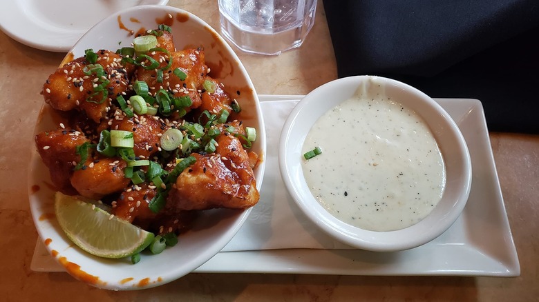 Overhead view of an order of Cheesecake Factory Korean fried cauliflower paired with a bowl of ranch