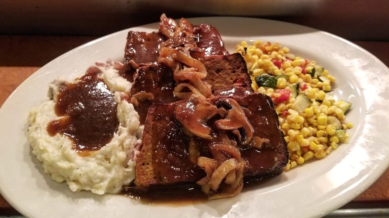 Close-up on a plate of Cheesecake Factory meatloaf with mashed potatoes and corn salad