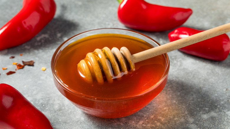 Organic hot honey inside of a bowl with a honey dipper