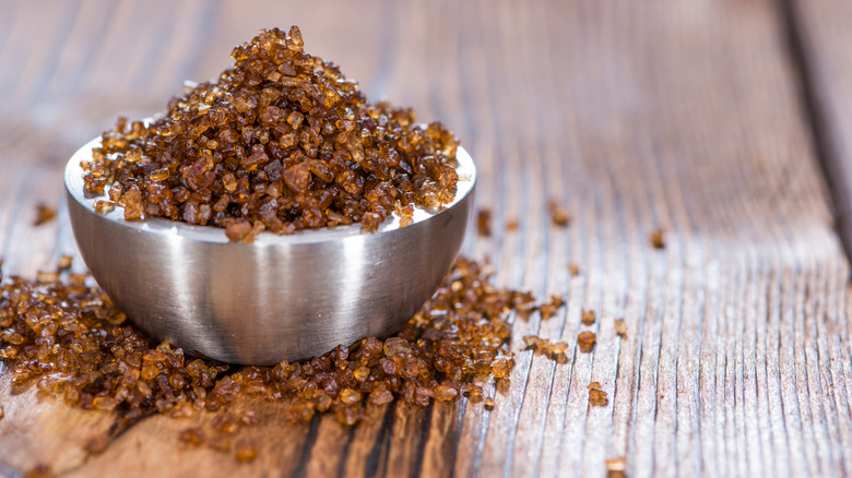 A small silver bowl of smoked salt on a wooden surface