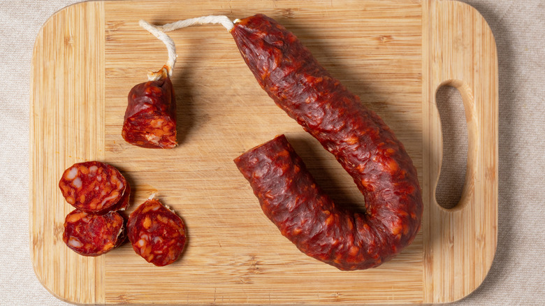 Sliced and whole red Spanish chorizo on a wooden cutting board
