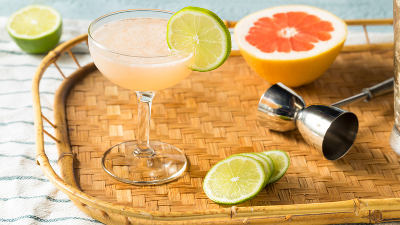 Hemingway daiquiri on woven tray with sliced grapefruit and limes