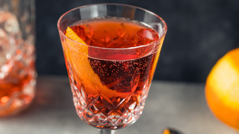 Close-up of negroni sbagliato sparkling cocktail with orange peel garnish