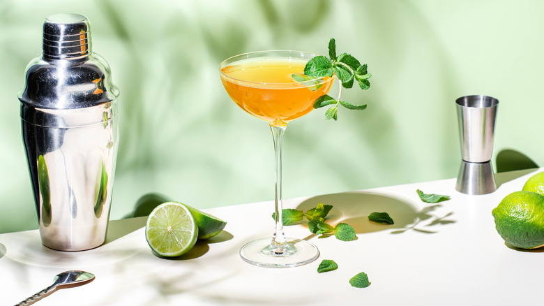 Old Cuban cocktail garnished with fresh mint, surrounded by bartending equipment and limes