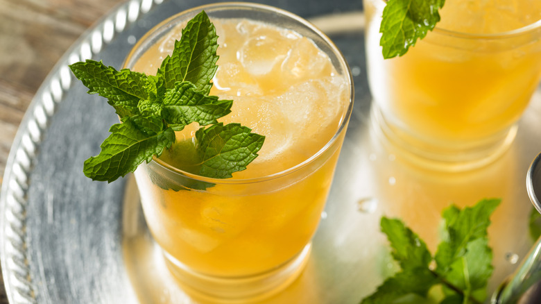Top view of whiskey smash cocktails on a silver tray, garnished with fresh mint