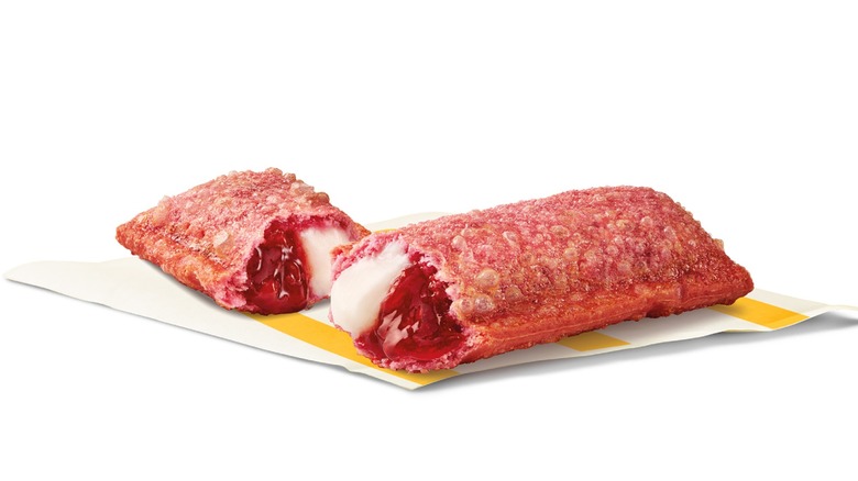 A pie with pink crust split to show the yoghurt and jam inside against a white background