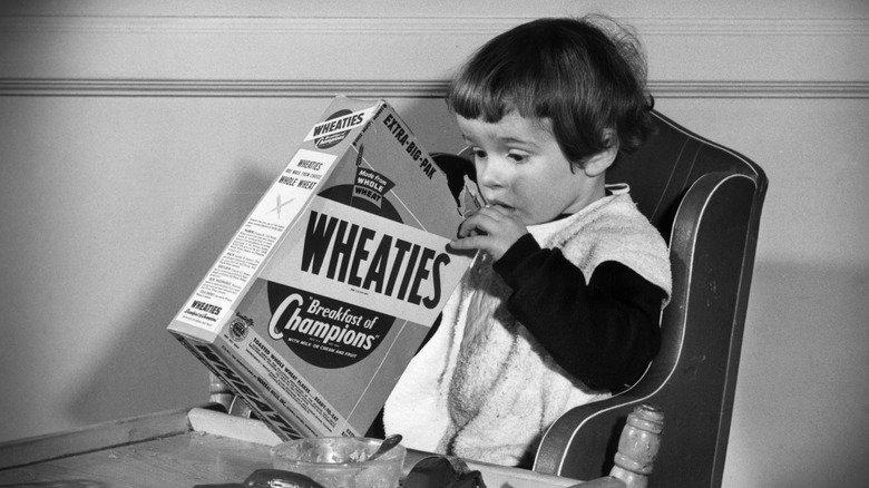 A child looking for a toy inside a cereal box from the 1950s