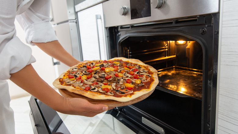 Woman putting pizza in oven