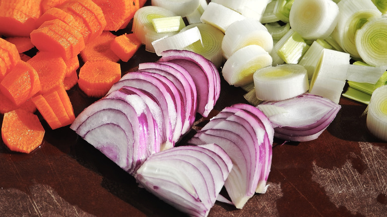 A close-up of chopped carrots, red onions, and leeks