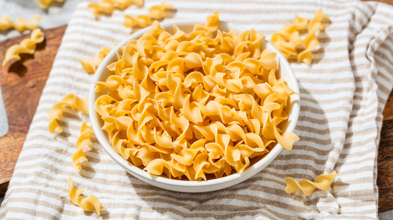Dry raw egg noodles in a white bowl on a dish rag