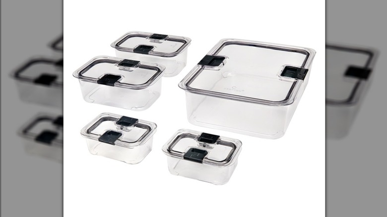 Five clear food storage containers of assorted sizes with lids against a white background.
