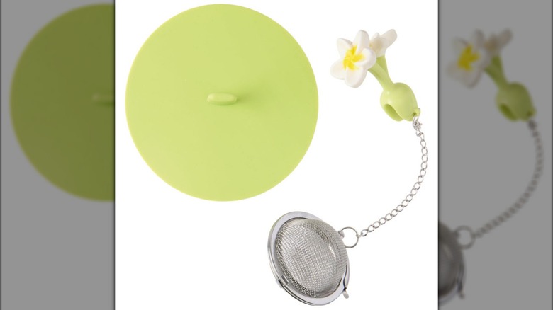 A lime green silicone lid and floral-shaped clip for a metal tea infuser against a white background.