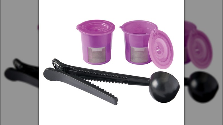 Two purple reusable KCups and a tool for filling and removing them against a white background.