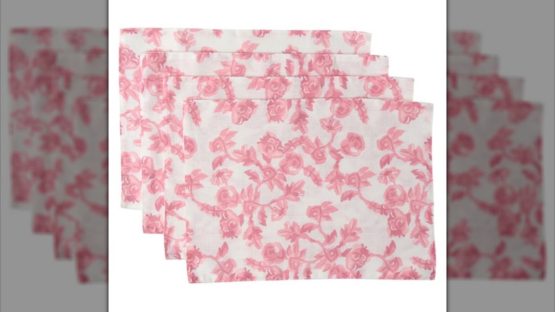 A stack of four pink and white floral print placemats
