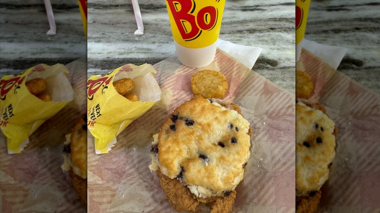 A Bojangles Bo-Berry biscuit sandwich, a drink, and hashbrowns on a table