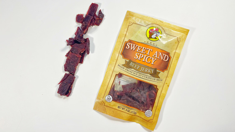 A bag of Sweet And Spicy jerky with a line of jerky next to it