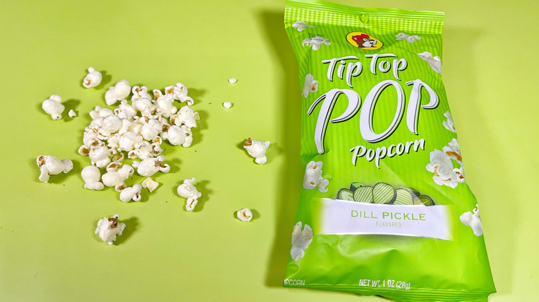 A pile of popcorn next to the bag of Tip Top dill pickle flavor