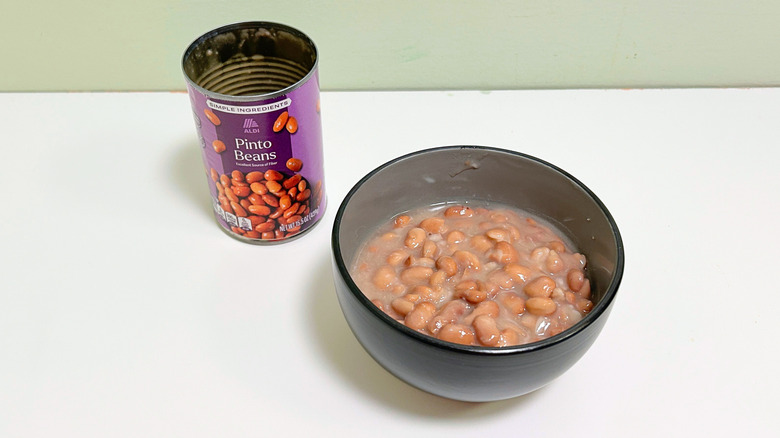 A can of Aldi Pinto Beans next to a bowl of pinto beans