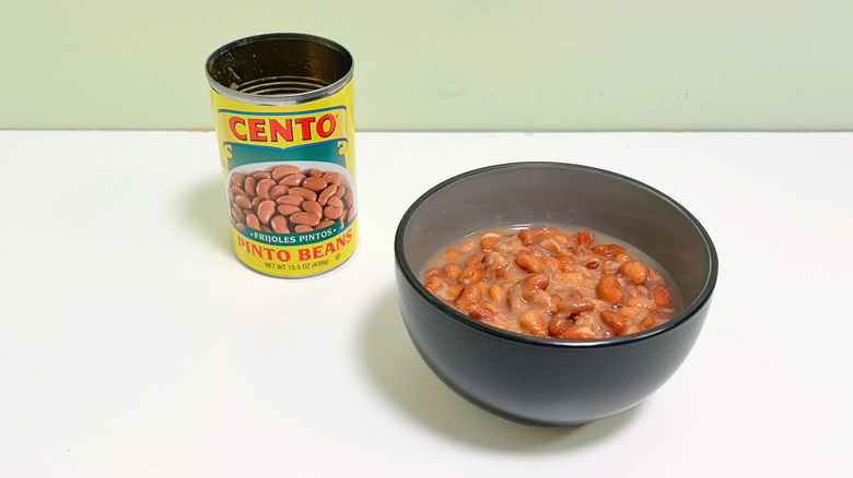 A can of Cento Pinto Beans next to a bowl of pinto beans