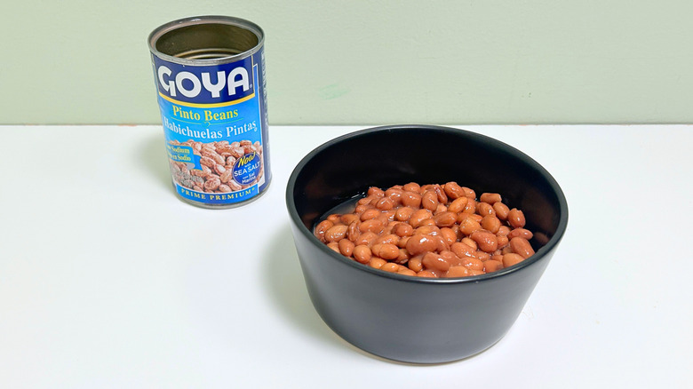 A can of Goya Pinto Beans next to a bowl of pinto beans