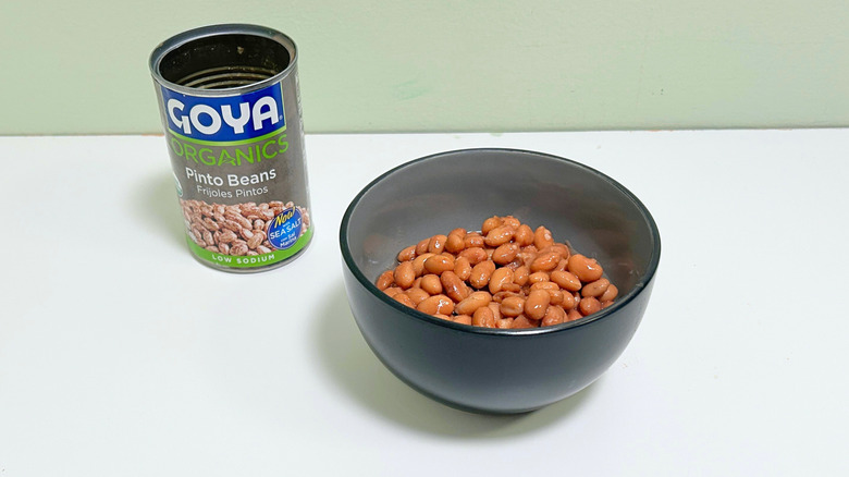 A can of Goya Organics Low Sodium Pinto Beans next to a bowl of pinto beans