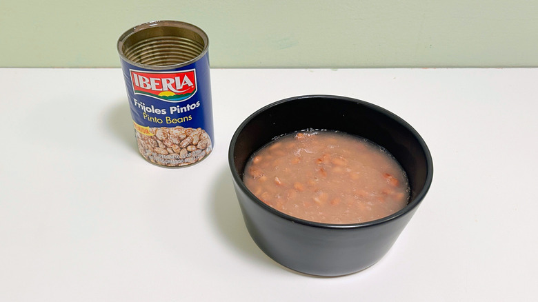 A can of Iberia Pinto Beans next to a bowl of pinto beans