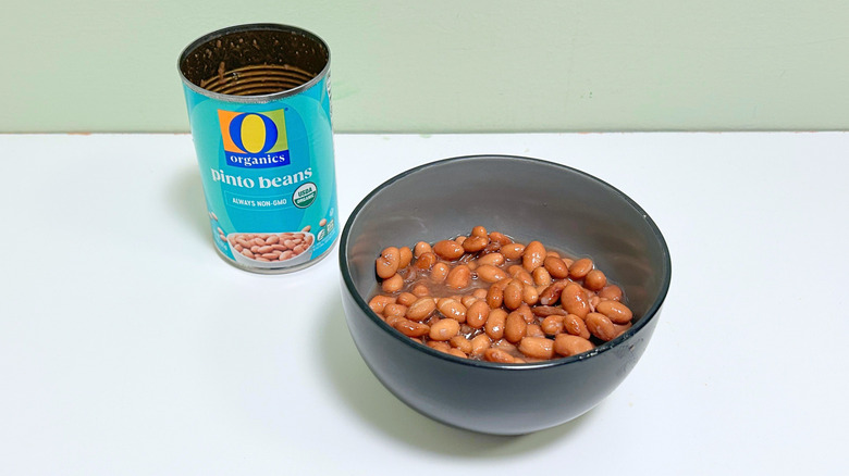 A can of O Organics Pinto Beans next to a bowl of pinto beans