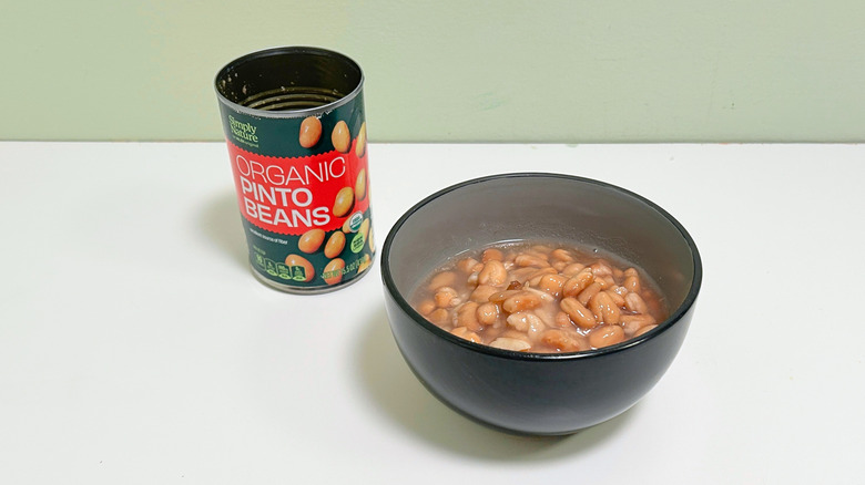 A can of Simply Nature Organic Pinto Beans next to a bowl of pinto beans