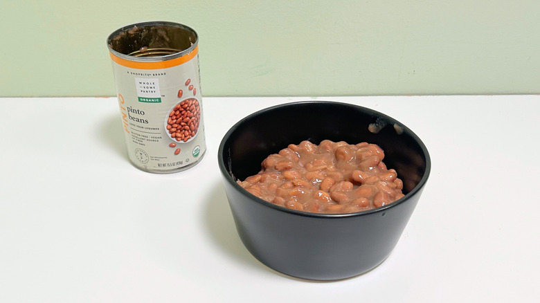 A can of Wholesome Pantry Organic Pinto Beans next to a bowl of pinto beans