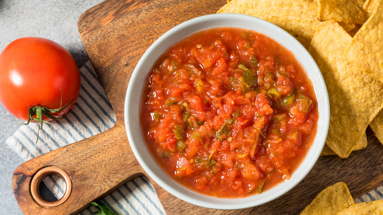 A bowl of homemade salsa framed against tortilla chips and a tomato