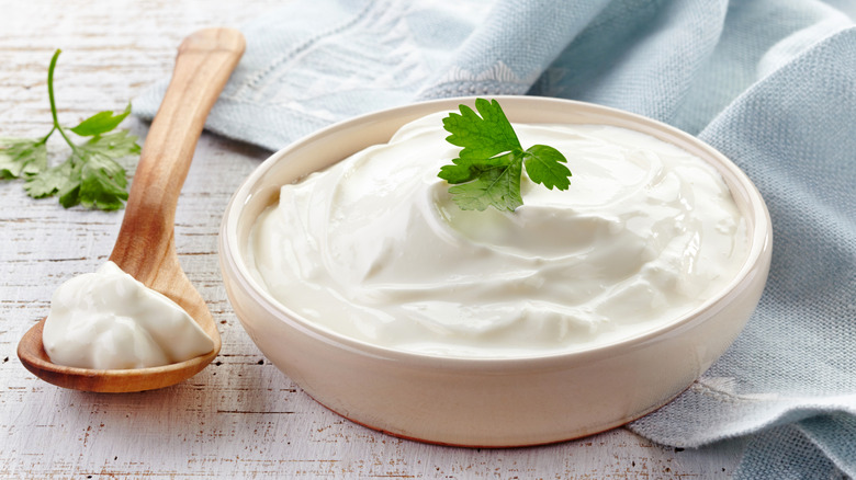 Sour cream in a bowl with a garnish next to a spoonful of sour cream