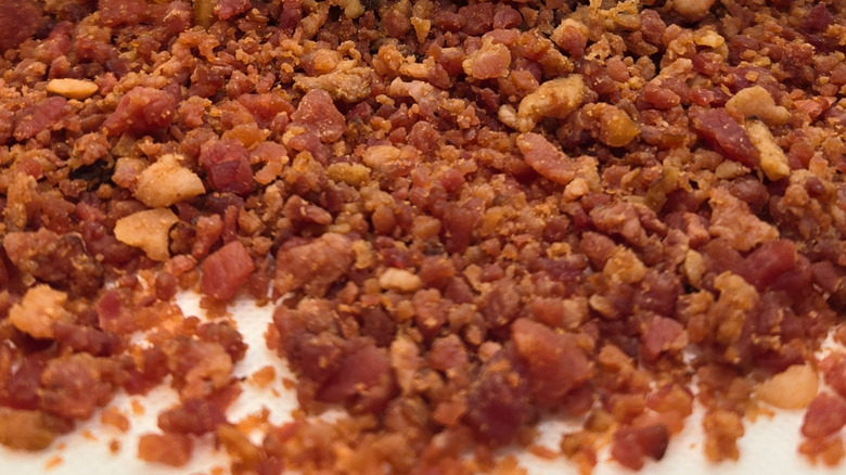 A close-up of bacon crumbles layered on a white surface