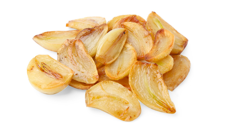 A pile of roasted garlic cloves isolated against a white background