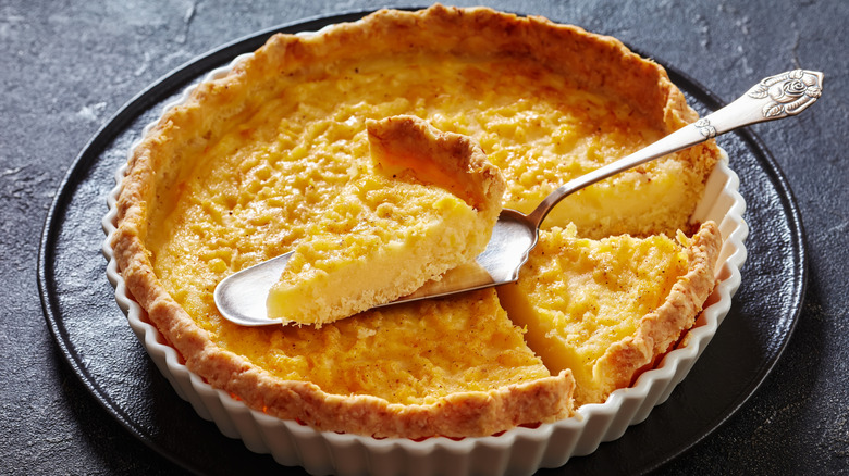 A dish of Chess pie has a slice removed and balanced on top.