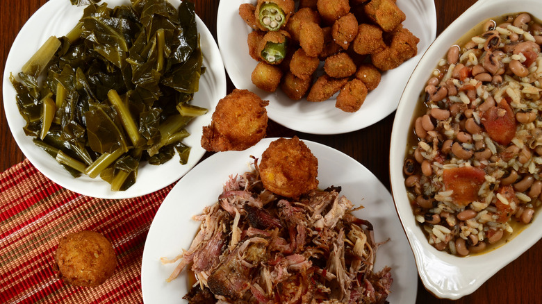 Collard greens, hush puppies, Hoppin' John, and pulled pork are served in plates.