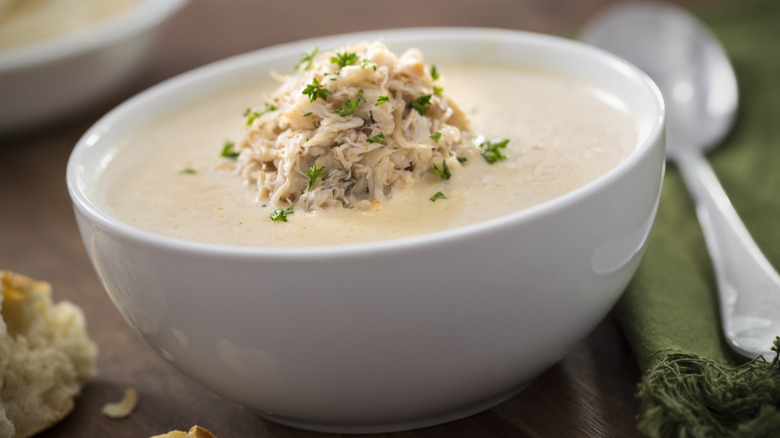 A white bowl is filled with she-crab soup and garnished with lump crab.