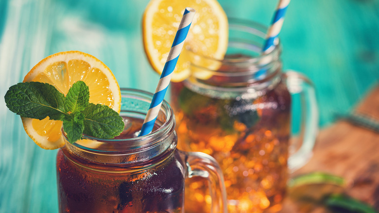 Two glasses of iced sweet tea are garnished with lemon wheels and mint.